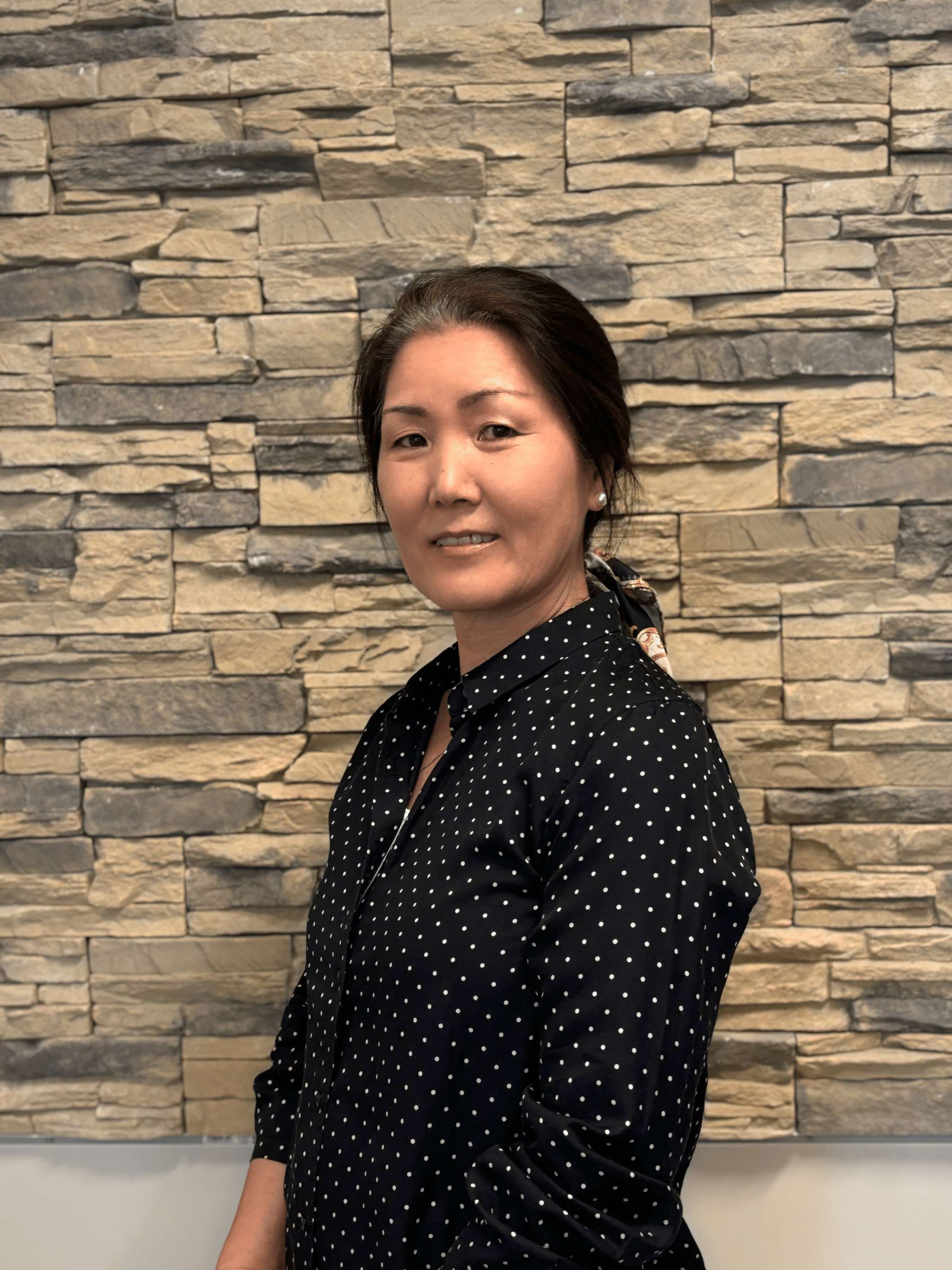 A woman standing in front of a brick wall.